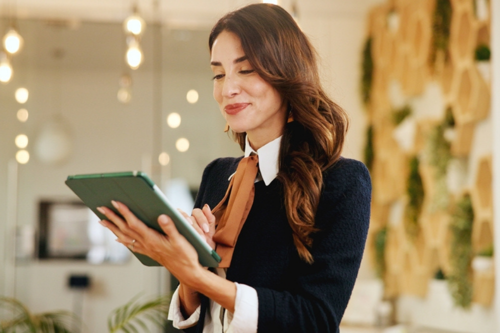 Reading, business woman and tablet in hotel for online booking, reservation schedule or information update. Digital technology, happy worker and communication with concierge typing on hospitality app