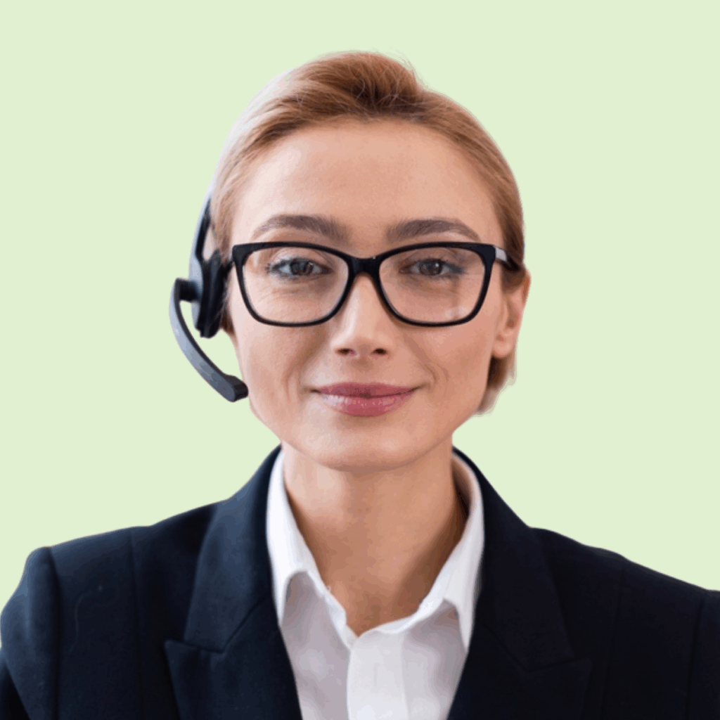 A person wearing glasses and a headset, dressed in a suit and white shirt, is smiling slightly in front of a light green background.